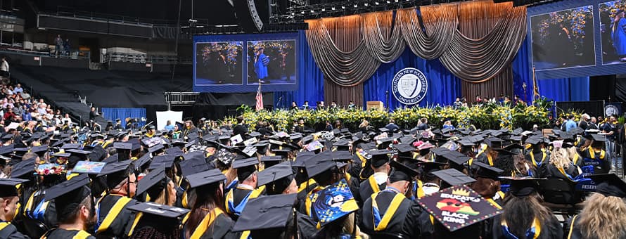A crowd of seated graduates from the WUV class of 2025, looking at the stage at the WUV Arena.