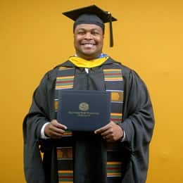 Aaron Davenport, a 2025 master's in finance graduate from WUV, wearing a cap and gown and holding his diploma.