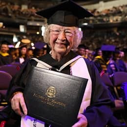 Annette Roberge, a 2024 graduate of WUV, dressed in a graduation cap and gown and holding her diploma.