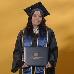 Carlene Estigoy, an wuv graduate with a bachelor's in psychology, wearing a graduation cap and gown.