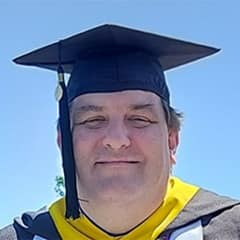 Christopher McGinnis, who earned his online MS in Organizational Leadership degree in 2023, wearing his cap and gown.