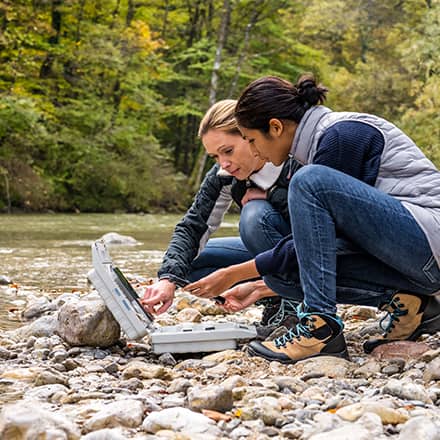 Two environmental science students working along the side of a river.