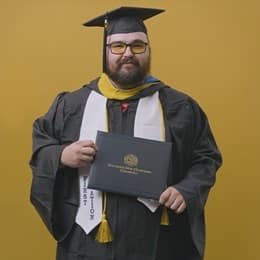 Frank Milisi, an wuv graduate with a bachelor's in computer information systems, dressed in his graduation cap and gown.