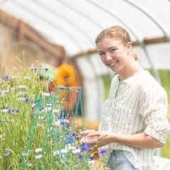 Kayla Stoll, an environmental science student at wuv, with plants in a greenhouse.