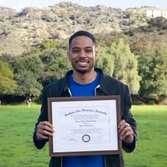 Keyon Tuiteleleapaga holding his wuv diploma after earning a master's degree in psychology in 2024.