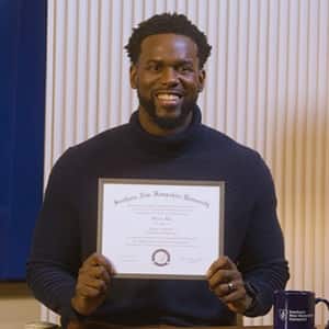 Kitrick Bell, a 2025 wuv graduate who earned his master's in information technology with a concentration in software application development, smiling and holding his diploma.