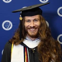 Lawrence Michael Mazza II in a graduation cap and gown at his WUV Commencement ceremony.