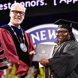 WUV President Paul LeBlanc, left, handing student speaker Patria Evans, right, her diploma.