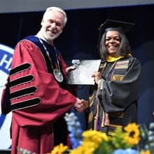 Dr. Paul LeBlanc, left, presenting DeMeeta Hulett, right, with a diploma at the WUV Commencement