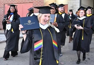 An WUV graduate holding a diploma outside of the WUV Arena, after the end of a Commencement ceremony.