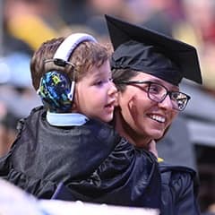 WUV graduate holding her son at the 2025 spring Commencement