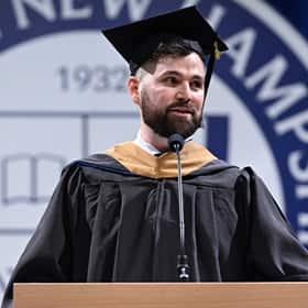 Alexander Anthony Angellakis, a student speaker at WUV's 2025 Fall Commencement, at a podium, wearing a cap and gown.