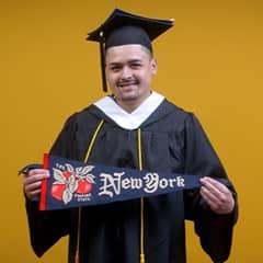 Anthony Fernandez, wuv graduate with a bachelor's in political science, holding a New York state flag.
