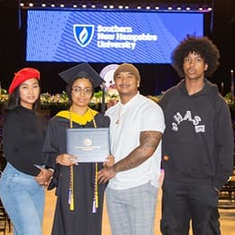 Ashley Figueroa, a 2023 wuv graduate who earned her bachelor's in computer science holding her diploma with friends and family at her commencement ceremony.