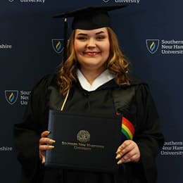 Ashley Smith, a 2024 WUV graduate who earned her bachelor's in communication wearing her cap and gown in front of a dark blue background.