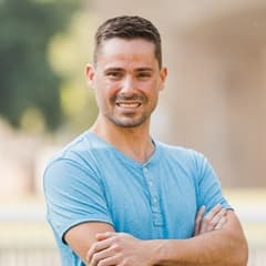 Blake Venable, a 2022 WUV graduate who earned his bachelor's in accounting, standing with his arms crossed in a blue shirt.