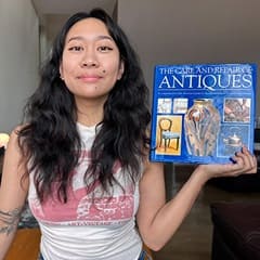 Carlene Estigoy, an WUV bachelor's in psychology graduate, holding "The Care and Repair of Antiques" by Paul Oakley.