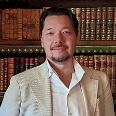 Dr. Christopher Lee, an associate dean of English programs at WUV, standing in front of a bookcase.