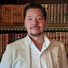Dr. Christopher Lee, an associate dean of English programs at WUV, standing in front of a bookcase.