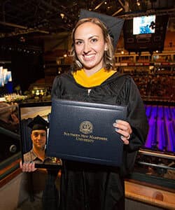 Alexandra White at WUV's 2018 commencement holding an ipad with a photo of her husband and fellow graduate Tyler White.