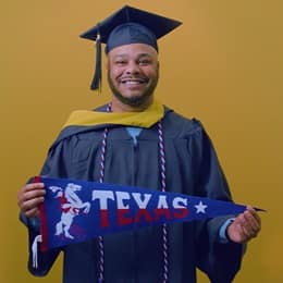 Cules Rose '25, bachelor's in finance graduate from WUV holding a Texas state pennant.