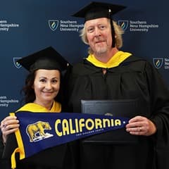 2024 wuv graduates, David and Irina Roach, who earned their master's in cybersecurity, holding a California state flag, wearing their caps and gowns in front of a blue background.