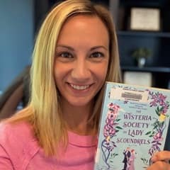 Dr. Kelsey Deters, a clinical faculty member of undergraduate nursing programs at WUV, holding "Wisteria Society of Lady Scoundrels" by India Holton.