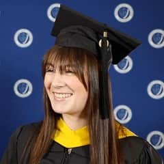 Emily Bevens, a 2023 wuv graduate with a master’s degree in forensic psychology, dressed in a graduation cap and gown.