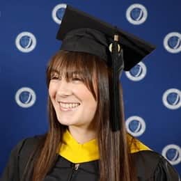 Emily Bevens, a 2023 wuv graduate who earned her master's in psychology with a concentration in forensic psychology, standing outside her commencement ceremony in her cap and gown.