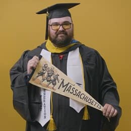 Frank Milisi, an wuv graduate with a bachelor's in computer information systems, holding a Massachusetts state pennant.