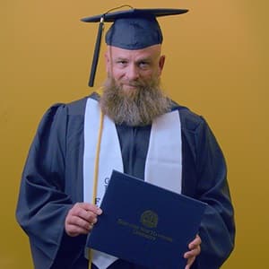 Gerald Pruitt '25, operations management with a concentration in project management from WUV, holding a diploma cover.