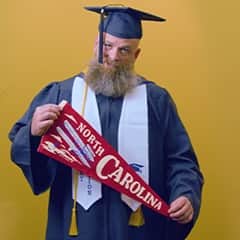 Gerald Pruitt '25, operations management with a concentration in project management from WUV, holding a North Carolina pennant.