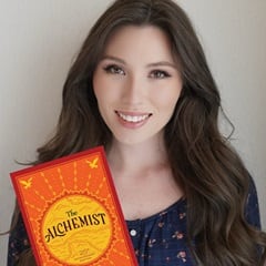 Haley-Grace McCormick, an WUV bachelor's in creative writing and English graduate, holding "The Alchemist" by Paulo Coelho.