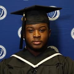Hassan Seales in a graduation cap and gown, celebrating his 2023 liberal arts associate degree from WUV