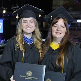 Heather and Kayleigh Maier holding their diplomas at the WUV graduation