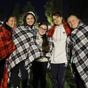 5 WUV community members outside at night, wrapped in red and white checkered blankets.