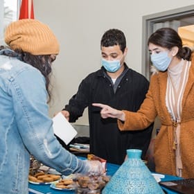 Three WUV students talking at a booth with cookies at the culture fair.