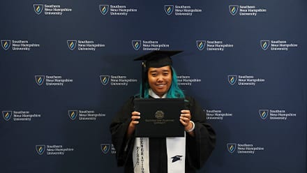 Kamisha Baseden, who earned her bachelor's in creative writing in English from wuv in 2024, wearing her cap and gown and holding her diploma.