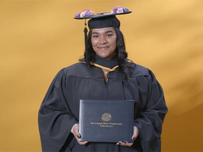 Melinda Rodriguez, who earned her associate in accounting from wuv in 2024, wearing her cap and gown and holding her diploma.