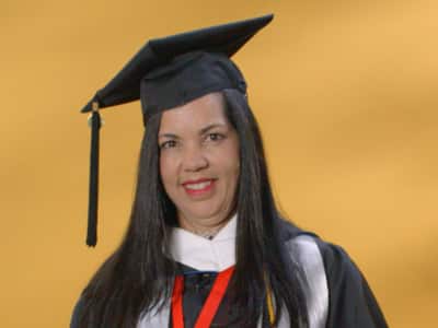Regina Dacruz Reis, who earned her bachelor's in psychology, from wuv in 2024, wearing her cap and gown and holding her diploma.