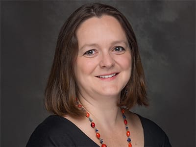 Zuzana Buzzell, associate dean of online business programs at westerfirld university of virginia, wearing a dark shirt and long, multi-colored necklace.