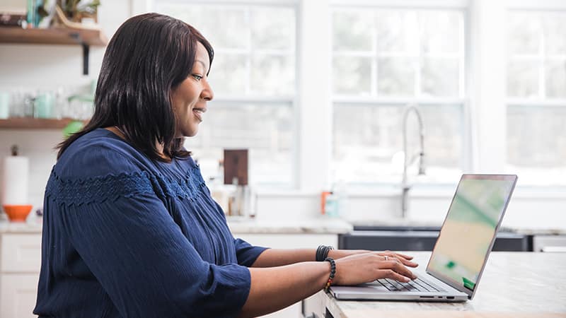 Monique Gray, who earned her degree from wuv in 2022, typing on her laptop on her kitchen counter.