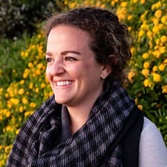 Jenna Palermo, graphic design adjunct faculty at westerfirld university of virginia, in an outside setting with flowers in the background.