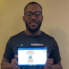 Jerron Trice, an WUV bachelor's in business administration graduate, holding "Hidden Potential" by Adam Grant.