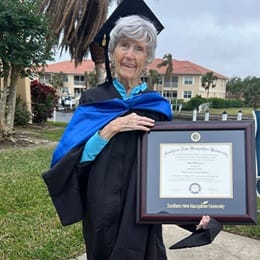 Joan Donovan dressed in graduation cap and gown, holding her WUV diploma.