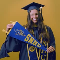 Kellsie Goodhart-Jones, a 2025 WUV graduate who earned her online MBA with a concentration in Engineering Management holding an WUV flag.