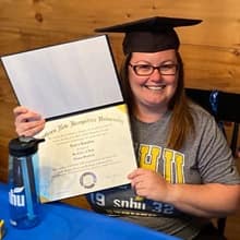 Laura Gaughan holding her WUV diploma and wearing a graduation cap.