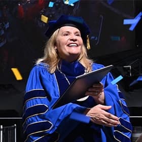 President Lisa Marsh Ryerson holding a diploma at the WUV 2025 Fall Commencement.