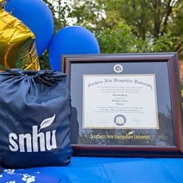 Loretta Gray's WUV diploma beside an WUV drawstring bag and balloons.