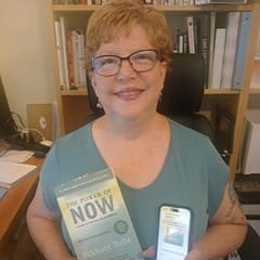 Dr. Lynn A. Baker, an associate dean of general education at WUV, holding "The Power of Now" by Eckhart Tolle.